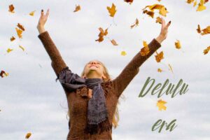 ragazza che alza le braccia al cielo tra le foglie d'autunno